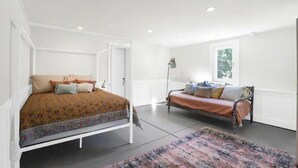 Une chambre à coucher avec un lit, un canapé, une lampe sur pied et une fenêtre.