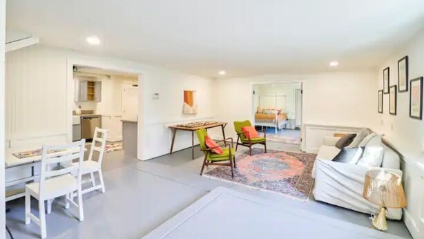 Un grand espace de vie comprenant un canapé, des fauteuils, une table à manger et une cuisine à l’arrière-plan.