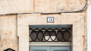 Una puerta doble con una placa que indica el número 74, ubicada en un muro de piedra.