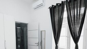 Una habitación de hotel moderna con una cama grande, zona de ducha y una pequeña mesa redonda.