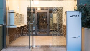 A modern building entrance with a glass door, a sign reading "WEST 3", and a "fort CAMBRIDGE" sign. - Luxury Seafront 3BR w/Pool by ArcoCollection (Sliema)