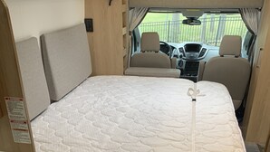 A compact RV interior with a bed, seating area, and a view of the outside. - 2020 Leisure Travel Rv Wonder at Boothbay Harbor, Maine!   (Boothbay)