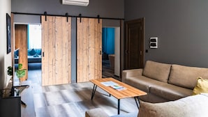 A modern living room with a sofa, a coffee table, and a sliding door leading to another room.