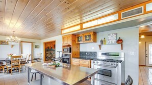 Une cuisine moderne avec des meubles en bois, un îlot central en acier inoxydable et un four encastré.