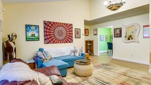 A living room with a blue sofa, a patterned rug, and various wall art.