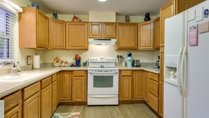 A kitchen with wooden cabinets, a white stove, and a refrigerator.