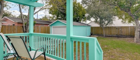 A turquoise deck with a pergola, a chair, and a shed in a backyard.