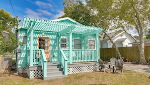 A turquoise house with a porch, a wooden deck, and a fenced yard.