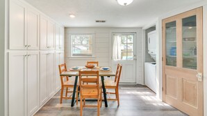 A kitchen with white cabinets, a wooden dining table, and chairs.