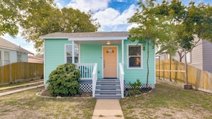 A small, single-story house with a front porch, a wooden fence, and a well-maintained lawn.