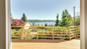 Eine Holterrasse mit Geländer, die auf einen See blickt, umgeben von Grünpflanzen und Bäumen.