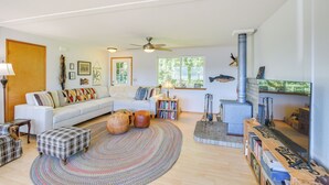 Ein gemütliches Wohnzimmer mit einem weißen Sofa, einem Kamin, einem Deckenventilator und einem großen Fenster.