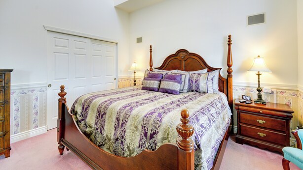 A bedroom with a wooden bed, a nightstand with a lamp, and a dresser. - Ocean Shores Condo w/ Private Tub < 1 Mi to Beach! (Ocean Shores)