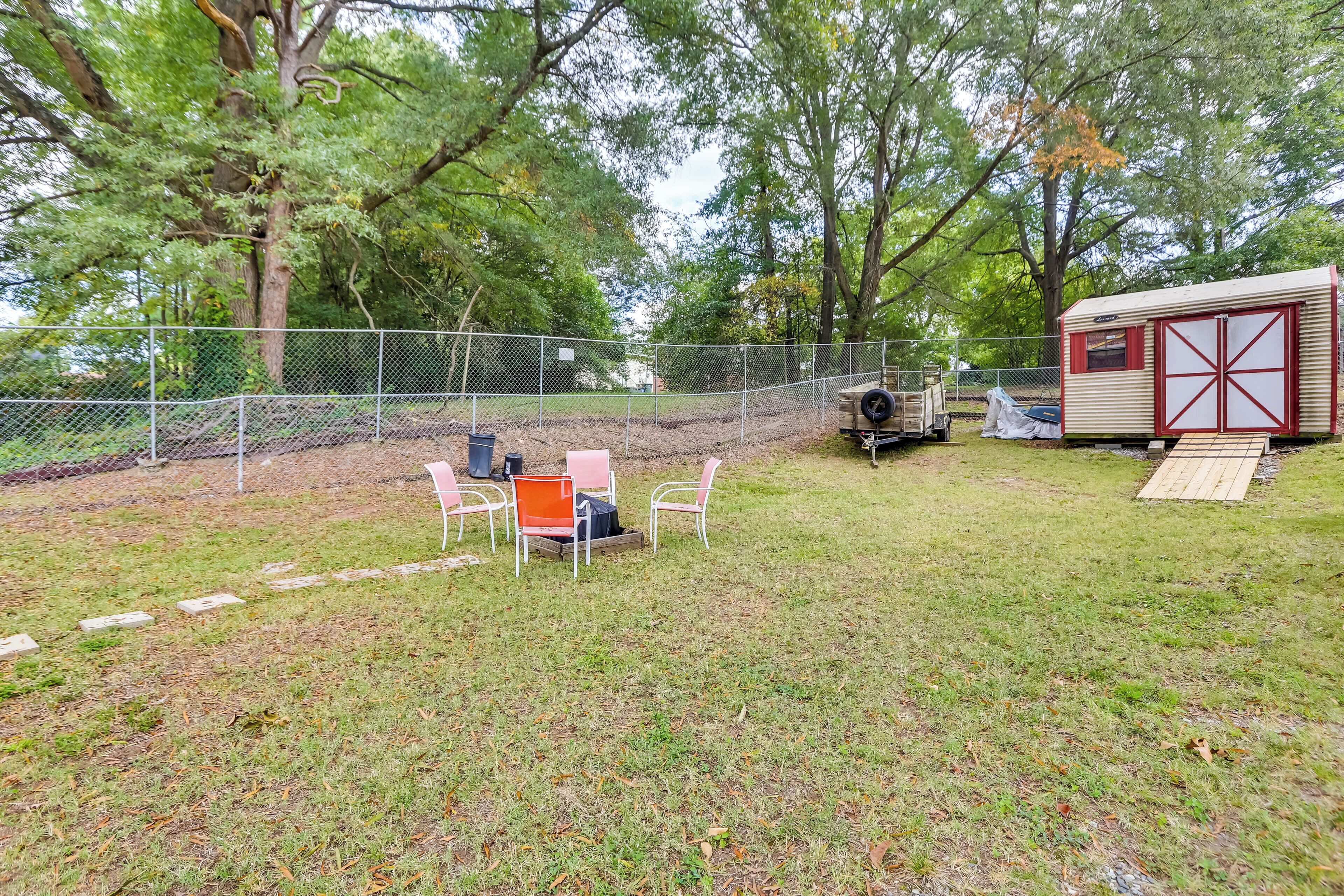 A fenced backyard with a small table and chairs, a portable grill, and a mobile home.