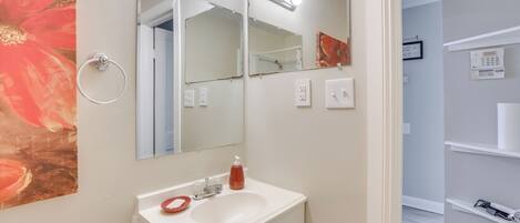 A bathroom with a white sink, two mirrors, and a ring light.