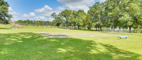 Un parc avec une aire de jeux, un banc bleu et une zone délimitée par une clôture.