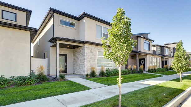 A row of modern townhouses with a stone facade, a well-maintained lawn, and a clear sky. - Inviting American Fork Home With Community Pool! (American Fork)