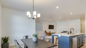 A modern kitchen with a central island, dining table, and chairs. - Inviting American Fork Home With Community Pool! (American Fork)