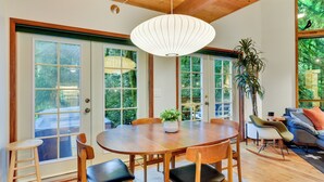 A dining area with a wooden table and chairs, a hanging light fixture, and a potted plant. - Rhododendron Creekside Cabin w/ Hot Tub & Fire Pit (Rhododendron)