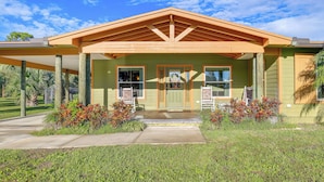 A house with a covered porch, a front door, and a small garden area. - Pet-friendly Fort Pierce Home w/ Screened Porch! (Fort Pierce)