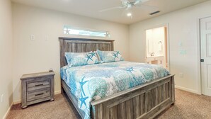 A bedroom with a wooden bed frame, a nightstand, a ceiling fan, and a window with a star decoration. - Pet-friendly Fort Pierce Home w/ Screened Porch! (Fort Pierce)