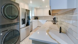 A modern kitchen with stainless steel appliances, white cabinetry, and a marble countertop. - Lake Texoma Vacation Rental: 1 Mi to Boat Ramp! (Pottsboro)