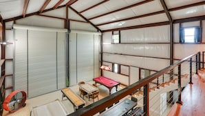 A spacious indoor area with a pool table, a red pool table, and a fan. - Lake Texoma Vacation Rental: 1 Mi to Boat Ramp! (Pottsboro)