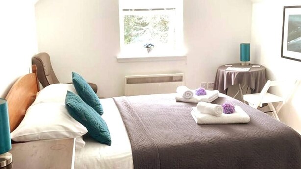 Een hotelkamer met een bed, een tafeltje, een stoel en een raam.