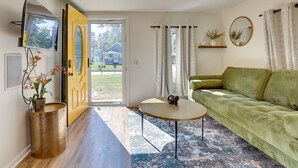Un salon moderne avec un canapé vert, une table basse ronde et une grande fenêtre.