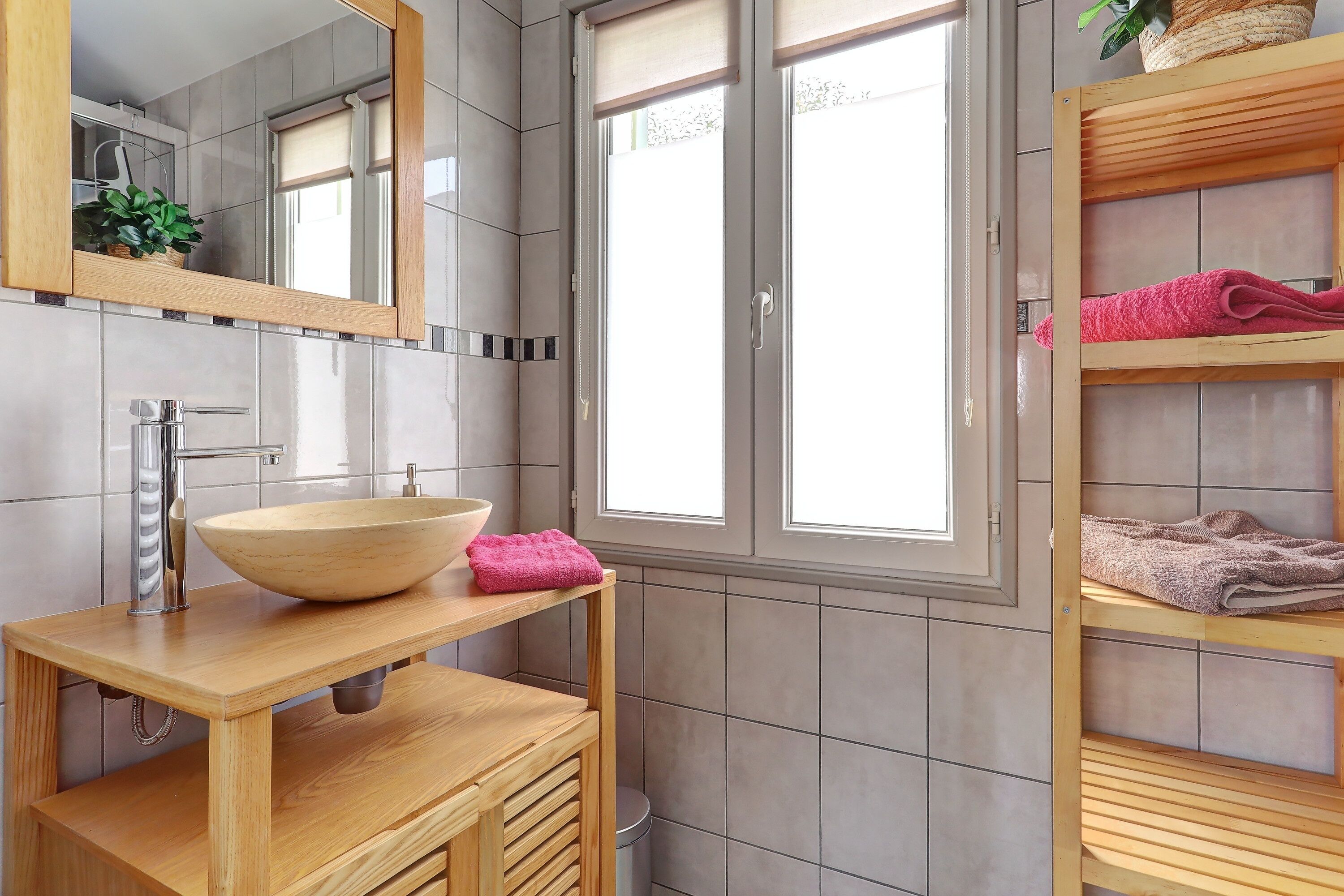 Un bagno moderno con un mobile vanitario in legno, un grande specchio e una finestra.