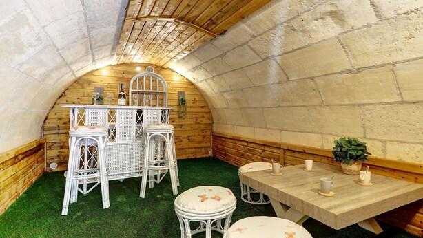 Un interno accogliente e rustico in legno, con un soffitto ad arco alto, un tavolo di legno con sedie e un piccolo angolo bar.
