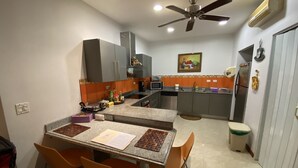 Una cucina compatta con zona pranzo, dotata di elettrodomestici moderni e una ventola a soffitto.