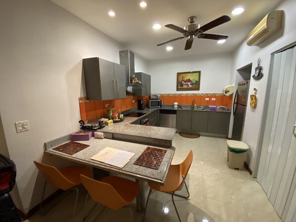 A compact kitchen with a dining area, equipped with modern appliances and a ceiling fan.