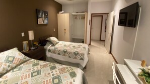 Una camera da letto con due letti, un ventilatore a soffitto, un condizionatore, una TV e un armadio.