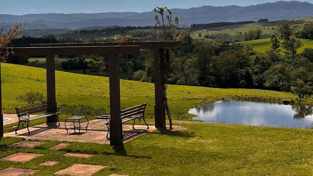 Un belvédère doté de bancs, offrant une vue sur un étang et un paysage pittoresque avec des montagnes à l’horizon.