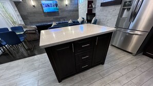 A modern kitchen with a granite countertop, dark cabinetry, and a stainless steel refrigerator.