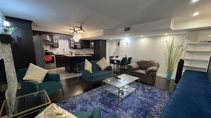 A modern living room with teal sofas, a glass coffee table, and a blue patterned rug.