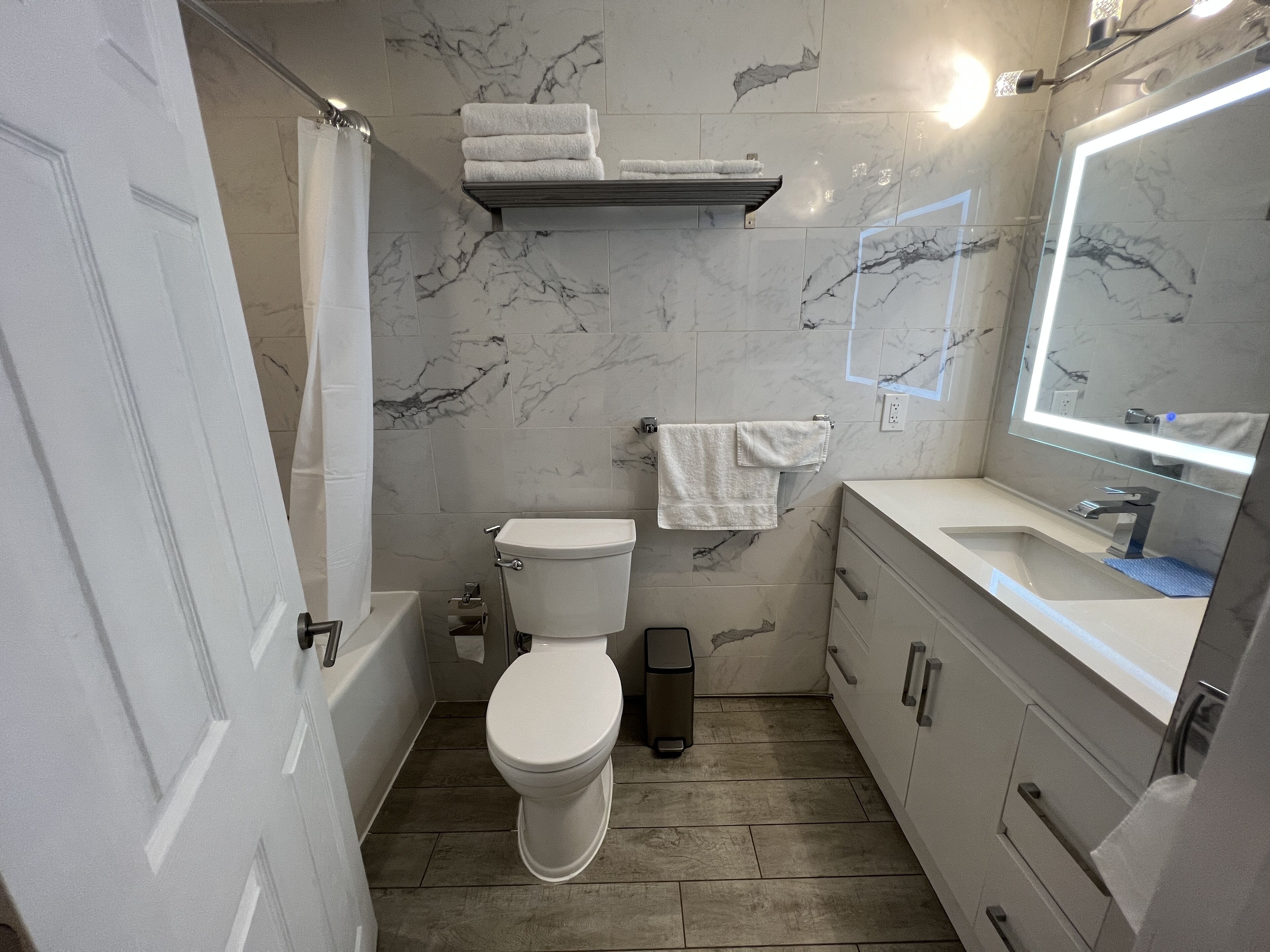 A bathroom with a toilet, sink, mirror, and a towel rack.