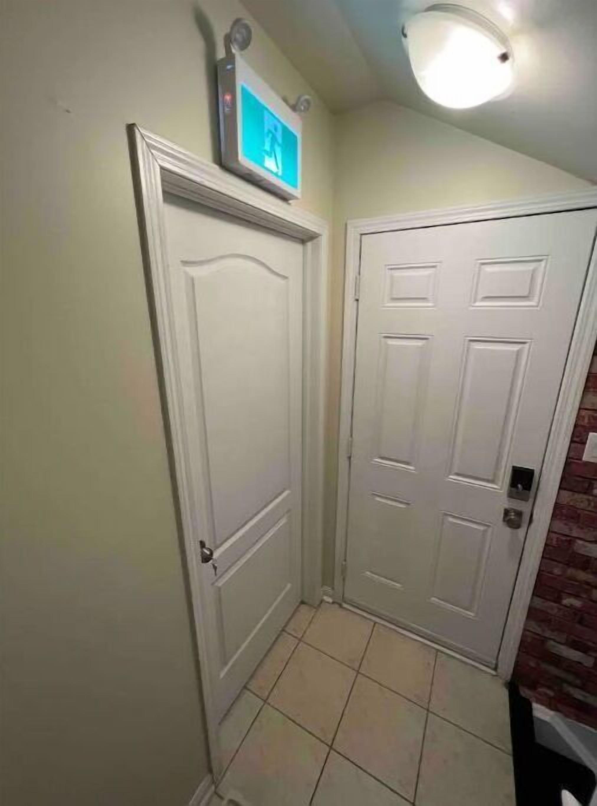 A hallway with two white doors, one with a picture frame above it, and a ceiling light.