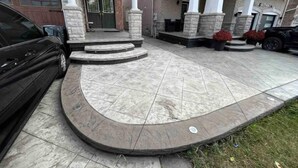 A house with a stone facade, a front porch with steps, and a driveway.