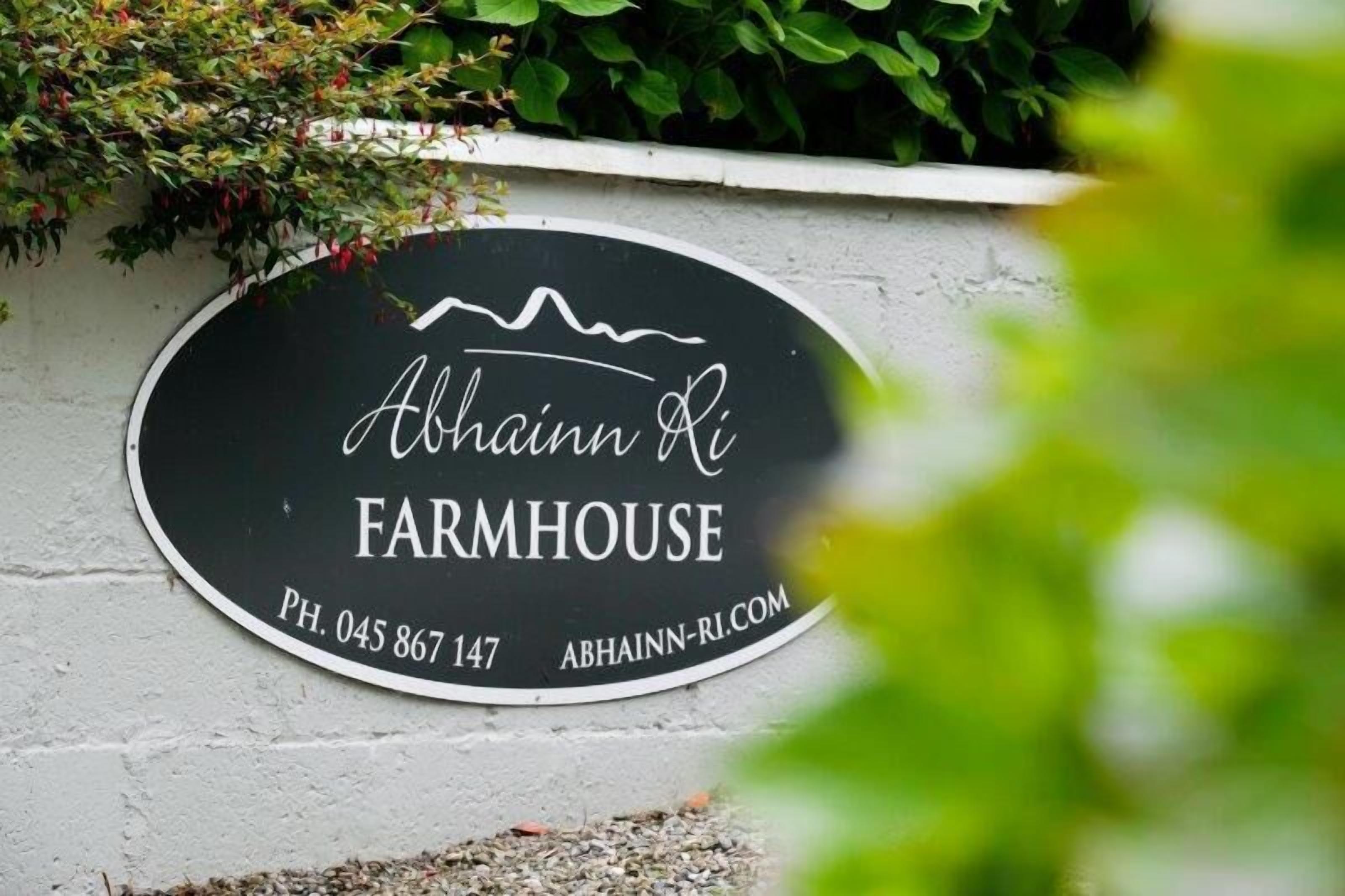 A black sign with white text reading "Abhaim Ri Farmhouse" and contact information.