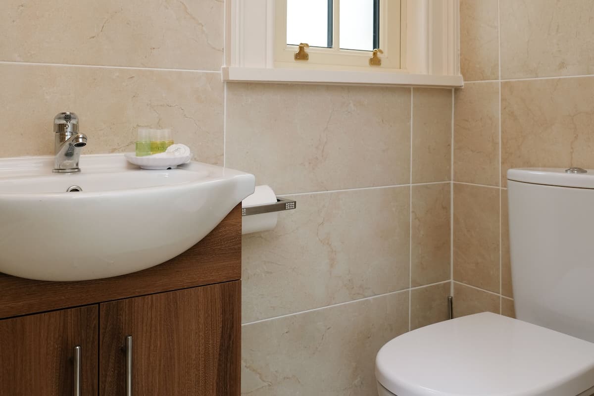 A bathroom with a white sink, wooden cabinet, and a toilet.