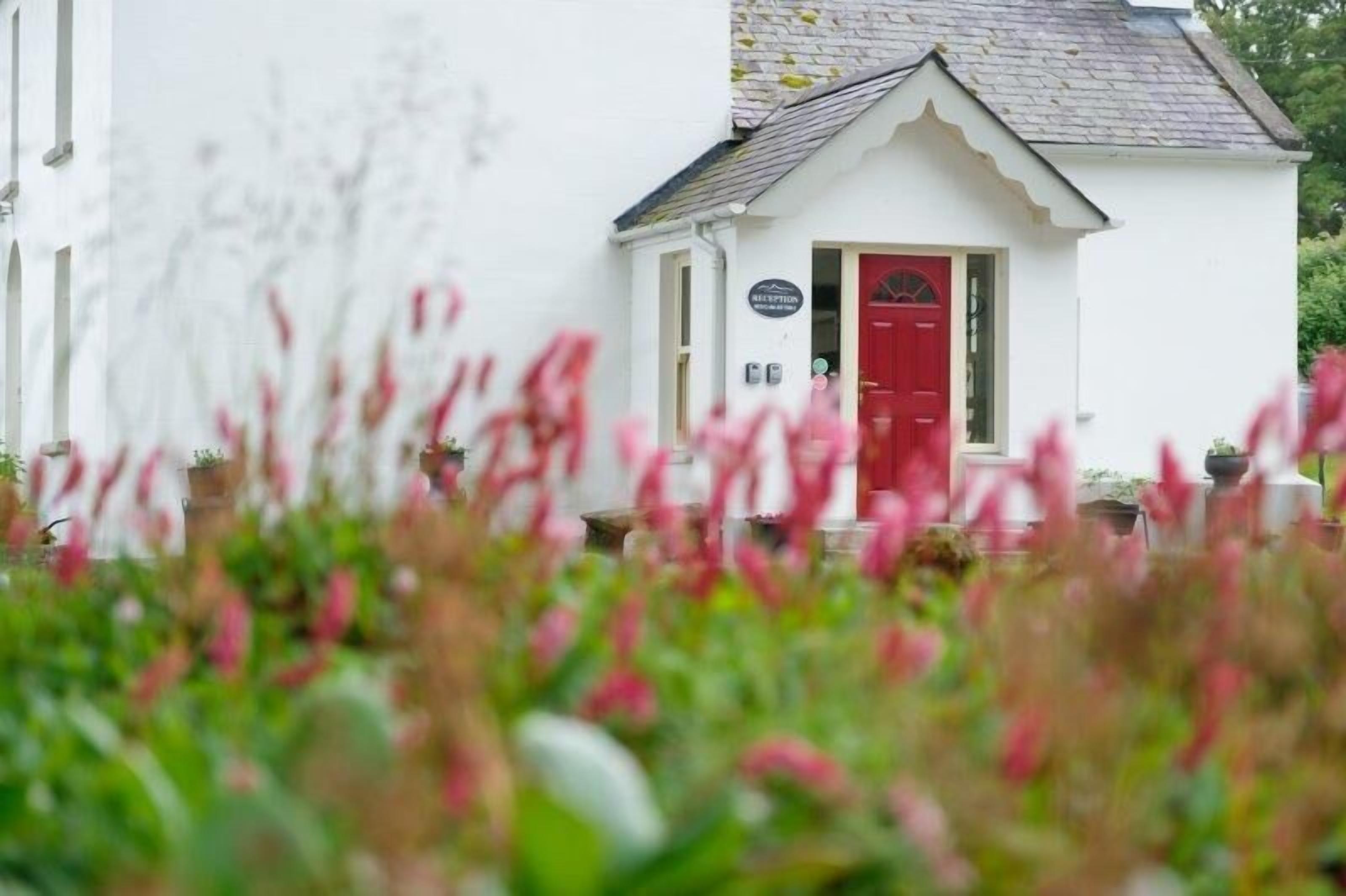 Un edificio blanco con una puerta roja y un cartel que dice "RECEPTION".
