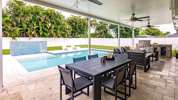 An outdoor patio with a pool, ceiling fans, and a barbecue area. - Fun in the Sun! Pool, Fenced Yard, Ping Pong, BBQ (Naples)