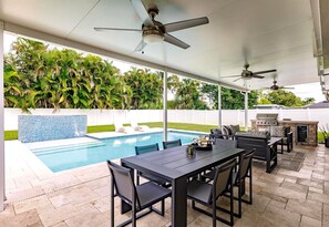 An outdoor patio with a pool, ceiling fans, and a barbecue area. - Fun in the Sun! Pool, Fenced Yard, Ping Pong, BBQ (Naples)