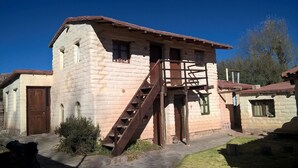 A rustic stone building with a wooden staircase leading to a loft area. - El Sol Hostel y Posada Humahuaca (Humahuaca)