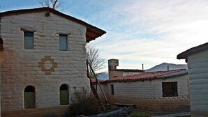 A rustic building with a stone facade, multiple windows, and a wooden staircase leading to the entrance. - El Sol Hostel y Posada Humahuaca (Humahuaca)
