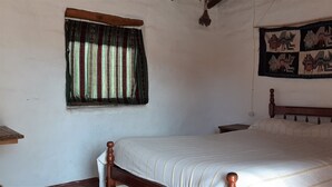 A bedroom with a wooden bed, a window with curtains, a wall hanging, and a small bedside table. - El Sol Hostel y Posada Humahuaca (Humahuaca)