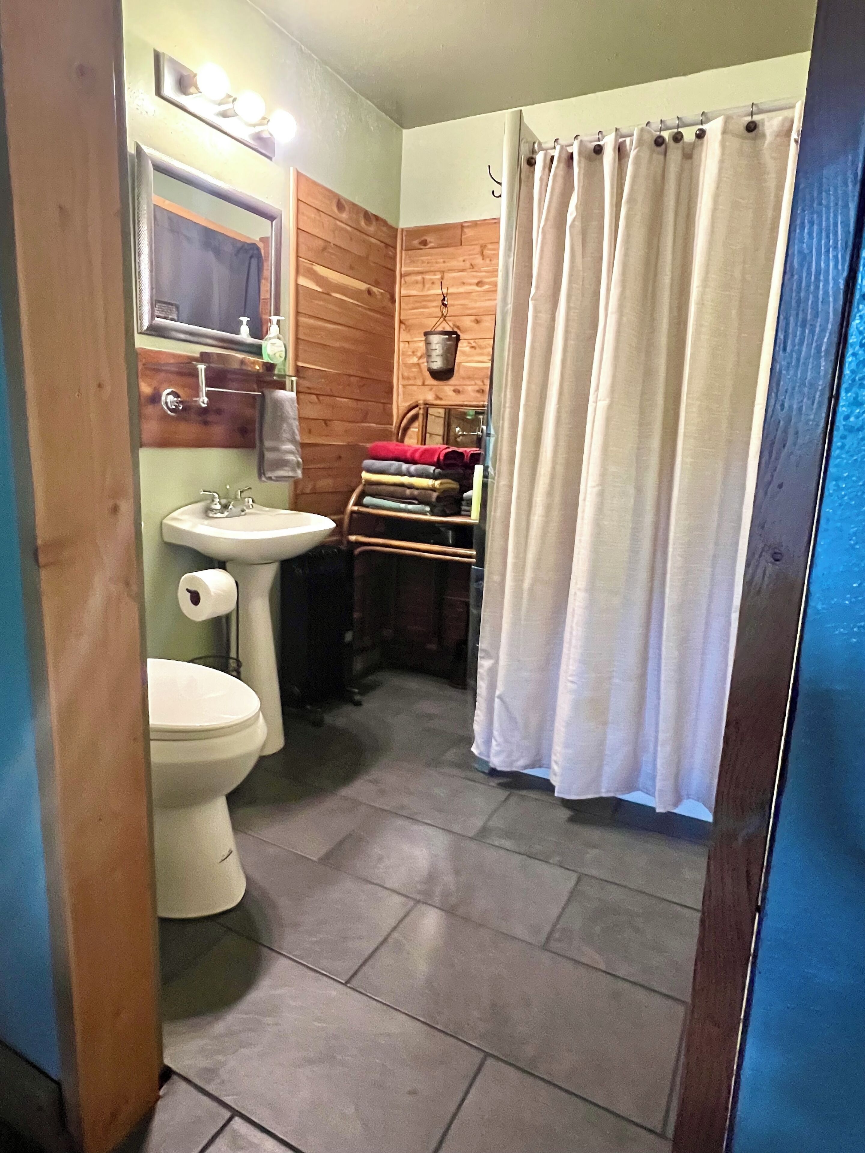 Ein kleines Badezimmer mit Toilette, Waschbecken und einer Duschvorhang.
