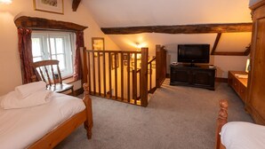Un dormitorio acogedor con cama de madera, televisor y escalera que lleva a un nivel superior.